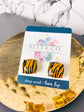 A pair of square stud earrings with an brown and black tiger-stripe pattern, mounted on a white display card with blue borders. The card is branded 'BEST & CO.